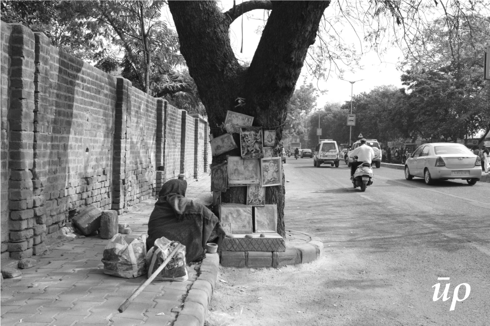 The old Limbdo (Azadirachta indica A.) tree marked as a shrine forms safe interim shelter for the elderly homeless woman during the day. This practice of in-habitation around tree represents typical beginning of roadside tree shrines that forms reoccurring wider pattern on streets.